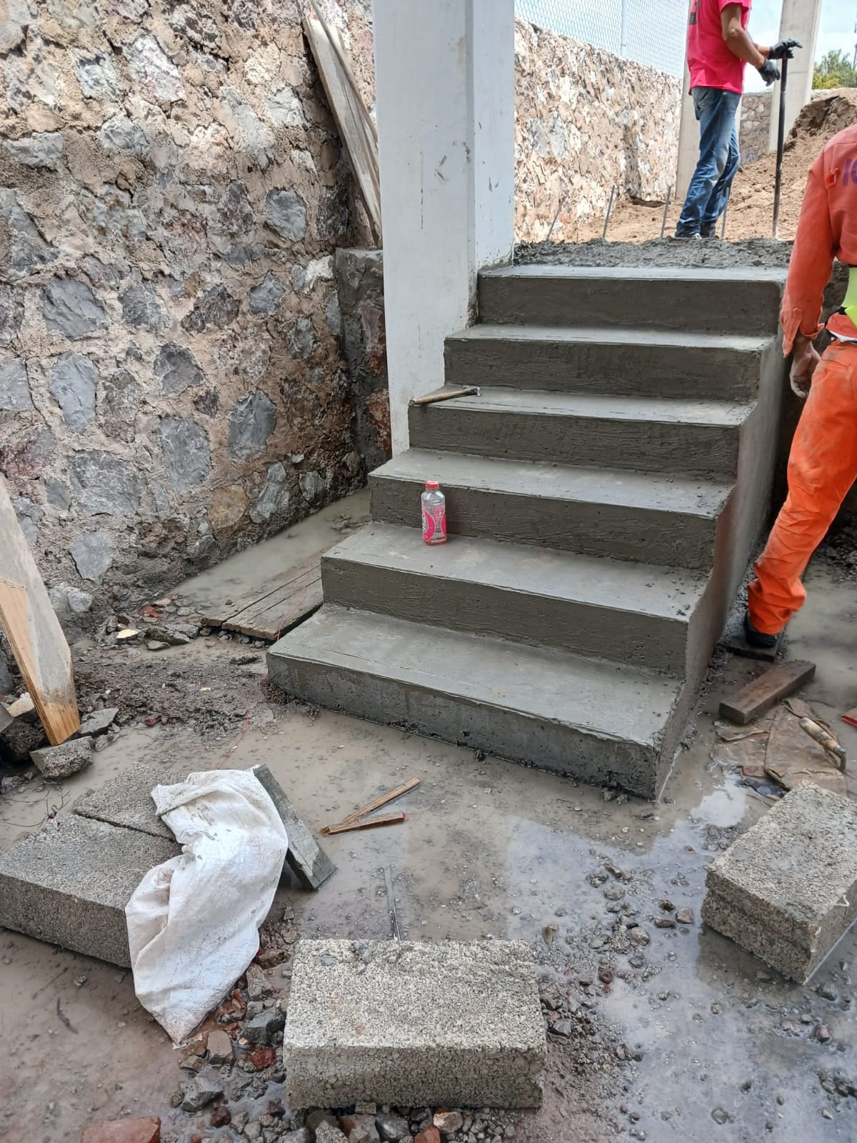 Escalera de concreto recién hecha junto a un muro de piedra