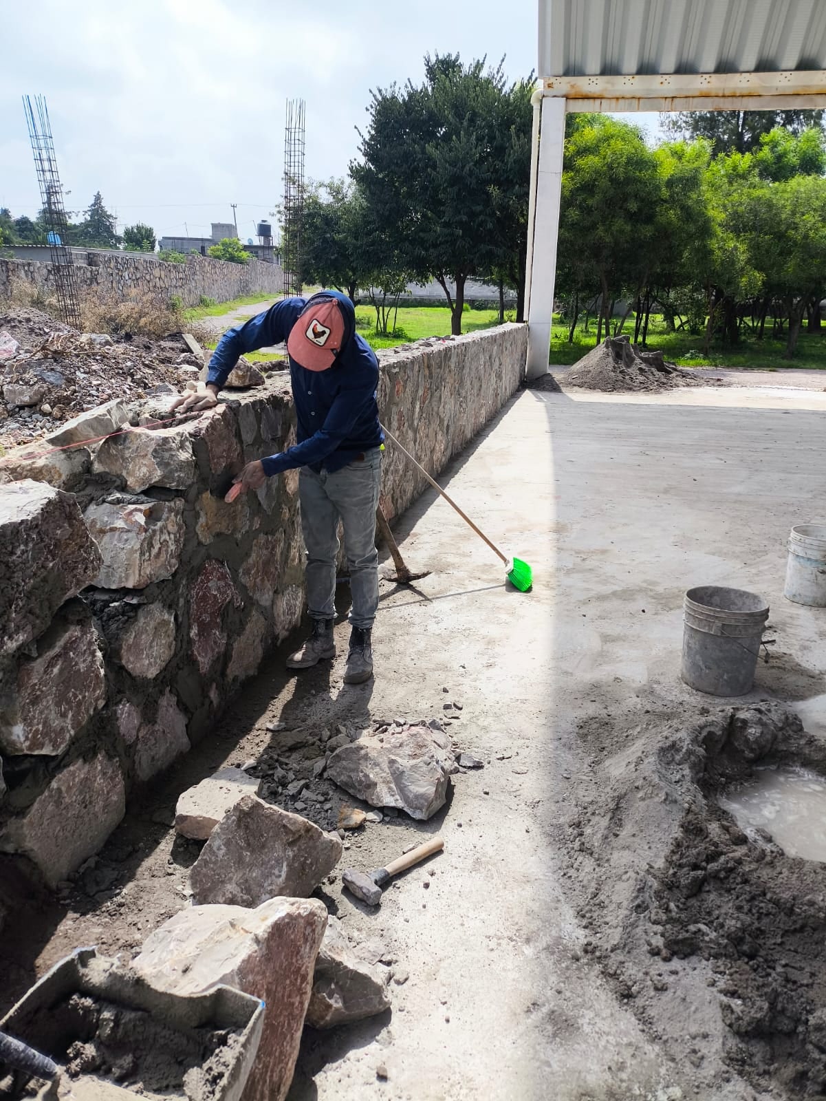 Albañil trabajando en un muro de piedra junto a la techumbre
