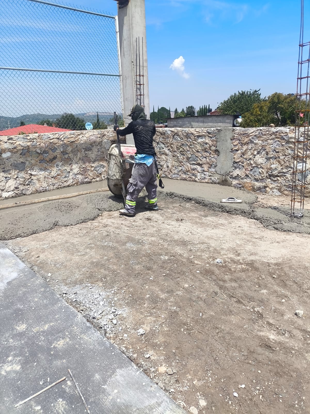 Albañil sobre un muro de piedra junto a la malla perimetral
