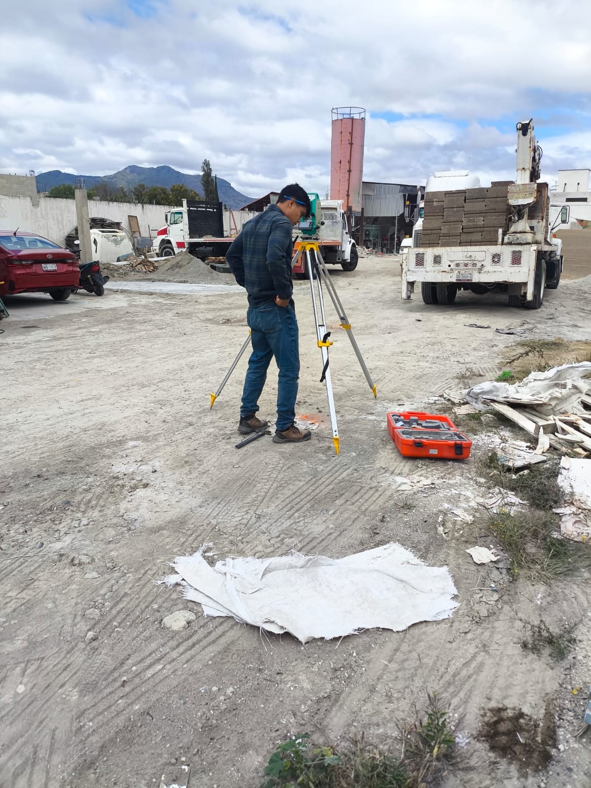 Topógrafo midiendo con la estación total en un predio junto a una obra