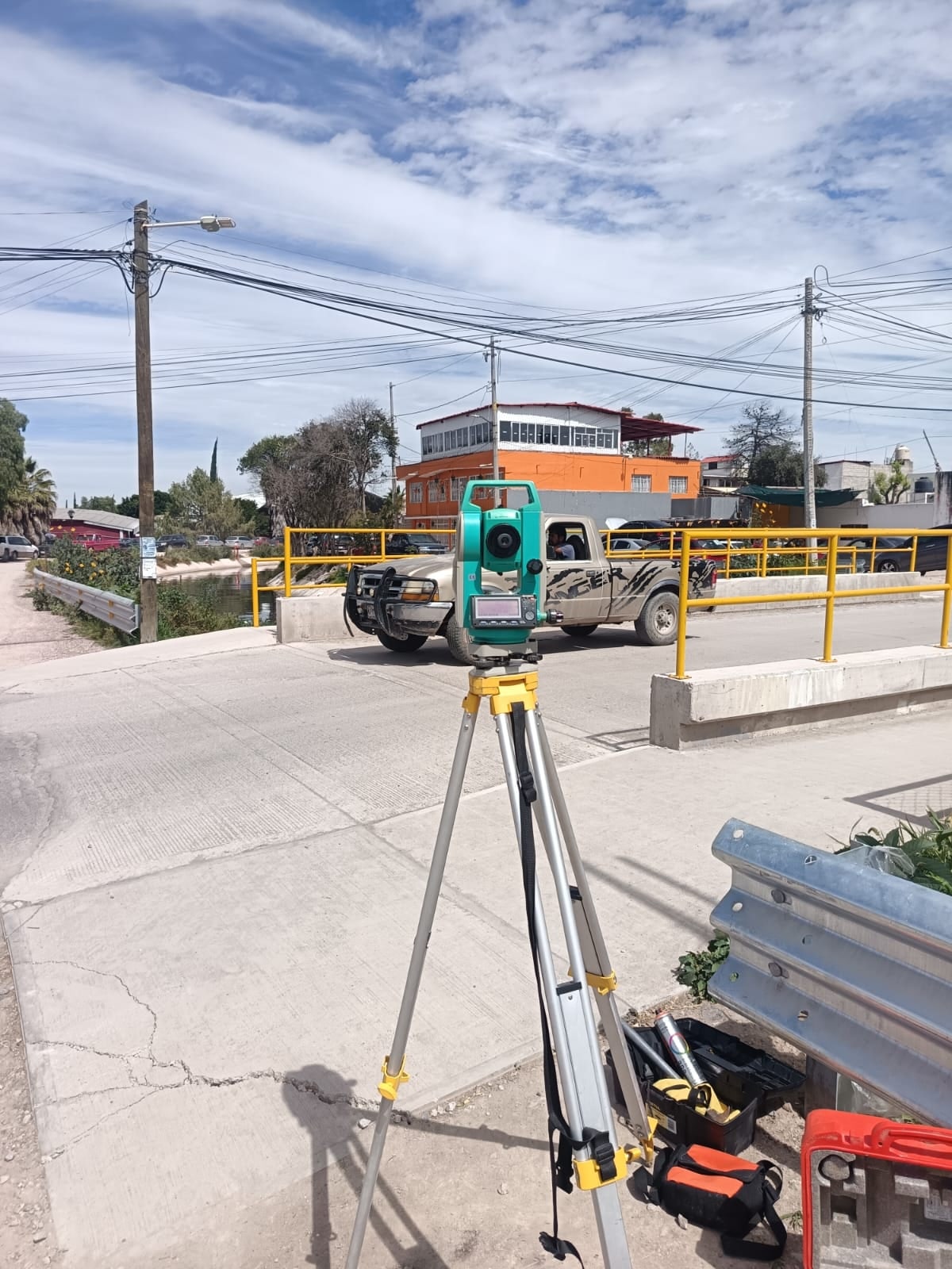 Estación total instalada en la calle, junto a un puente